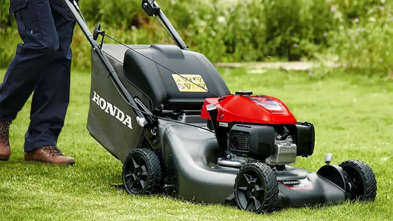 a man pushing a petrol lawnmower